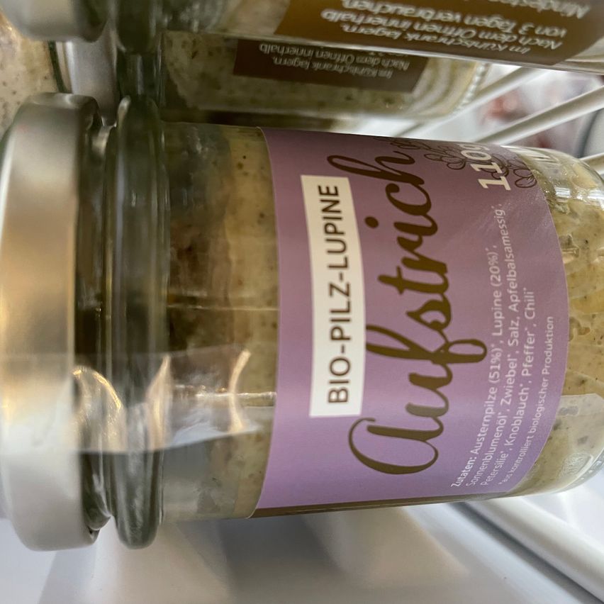 Ein Glas mit Bio-Knoblauch-Pfeffer-Sauce steht auf einem Regal. Es ist mit 'BIO-PILZE-LUPINE' beschriftet und enthält Zutaten wie Knoblauch, Pfeffer und Lupine.