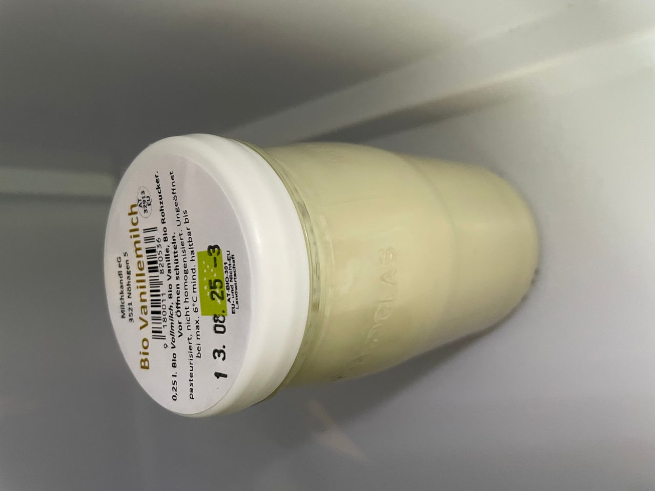 Ein zylindrischer Behälter von Bio Vanillemilch, mit einem Strichcode und einem grünen Etikett, das anzeigt, dass es pasteurisiert und verzehrfertig ist.