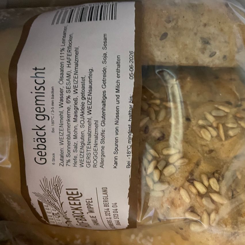 Ein Nahaufnahme eines verpackten Brotgemisches mit Samen, das seinen Etikett zeigt mit Zutaten und Nährwertangaben. Das Etikett enthält den Namen 'Gebackt gemischt', das Datum '05-06-2026' und verschiedene Zutaten.