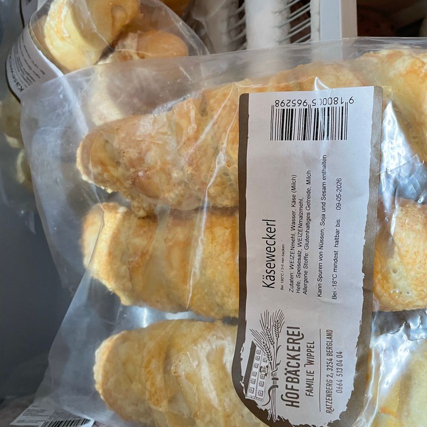 Mehrere Packungen Käsecroissants, gekennzeichnet mit einem Strichcode und Zutaten. Die Croissants sind goldbraun, möglicherweise mit Käse gefüllt.