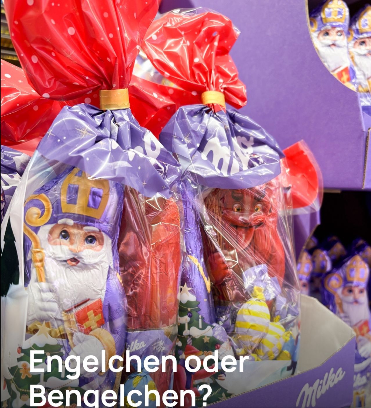Zwei Packungen Schokolade mit Weihnachtsmann-Designs sind in rote und lila Schleifen eingewickelt. Der Text 'Engelchen oder' steht in Weiß auf den Packungen.