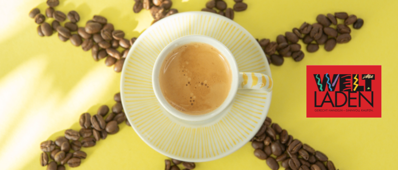 Eine Tasse Kaffee umgeben von Kaffeebohnen, die in einem Sonnenmuster auf einem gelben Hintergrund angeordnet sind. Das Bild enthält auch die Worte Welt Laden.
