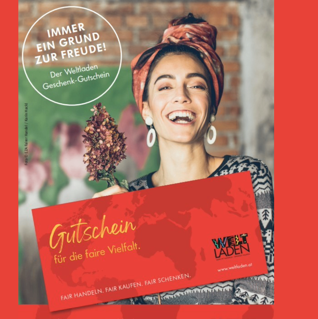 Eine lächelnde Frau hält eine rote Geschenkkarte mit dem Text 'Gutschein für die faire Vielfalt'. Der Hintergrund zeigt eine Backsteinmauer mit Grünpflanzen. Die Karte zeigt eine Weltkarte und die Website 'www.weltladen.at'.