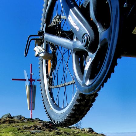 Vorderrad eines Mountainbikes und das Mugel-Gipfelkreuz