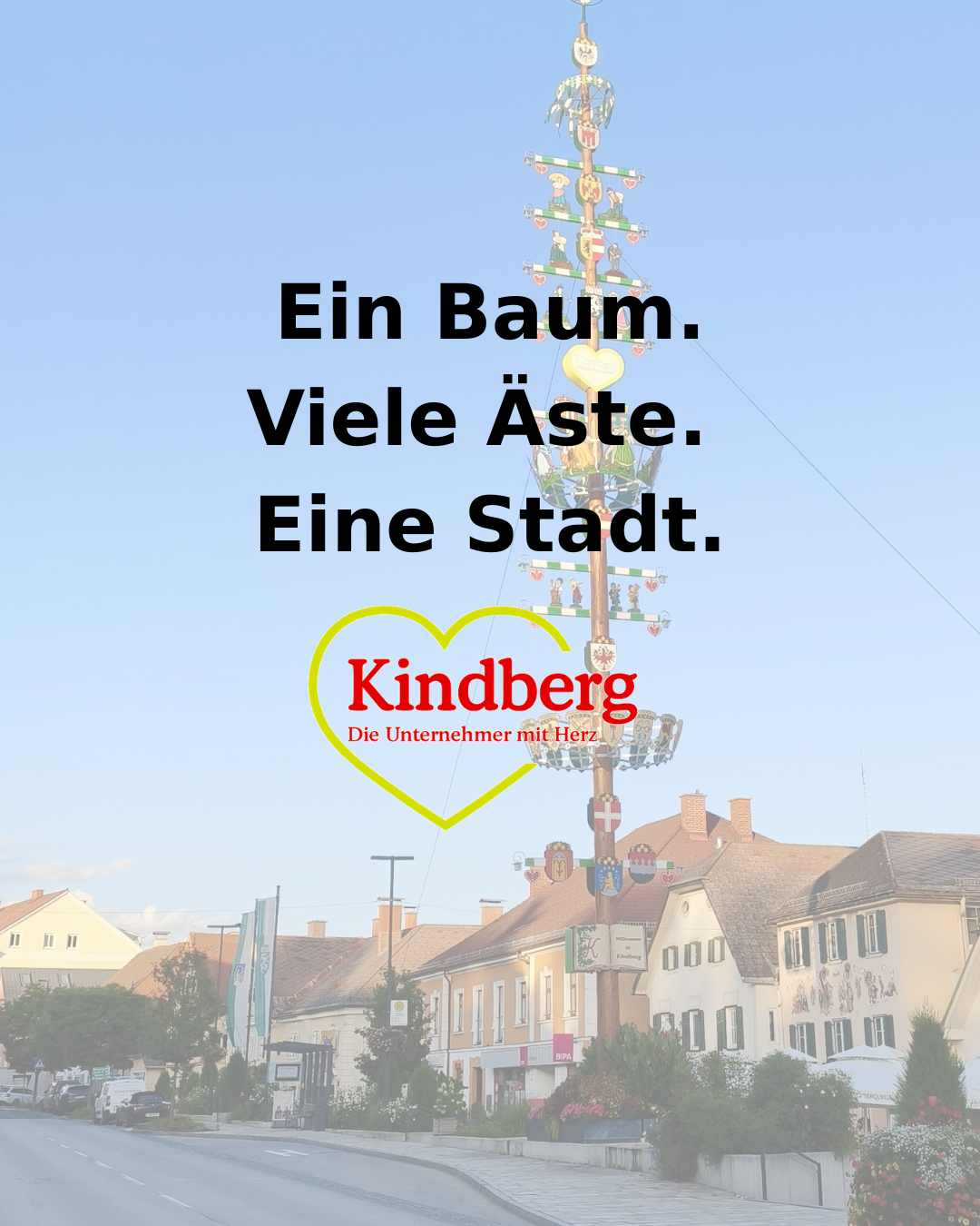 A tree with many branches and a heart shape in the center. The words 'Ein Baum. Viele Äste. Eine Stadt.' are written above it. The image features a cityscape with buildings and a clear blue sky.