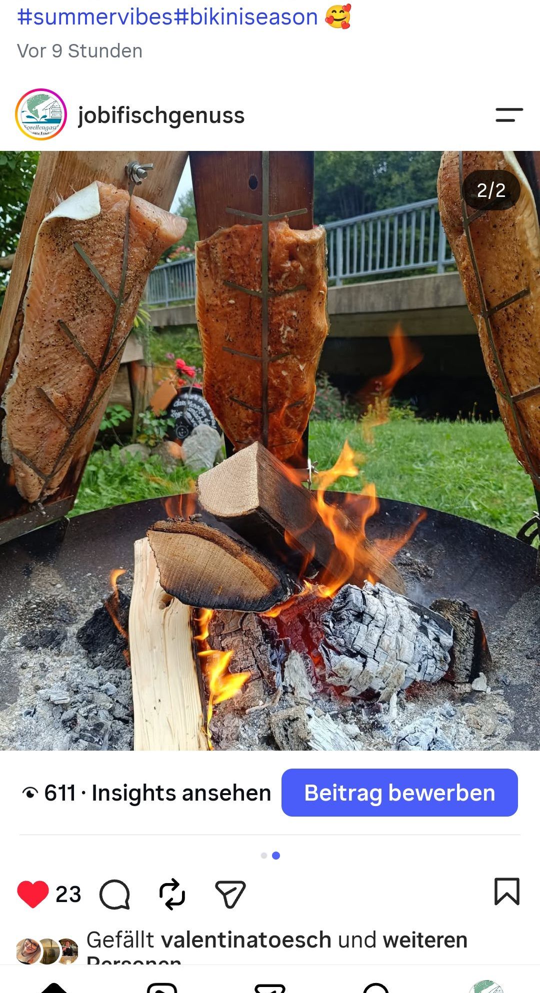 A fire pit with burning wood and flames, with three pieces of meat being cooked on sticks above the fire.