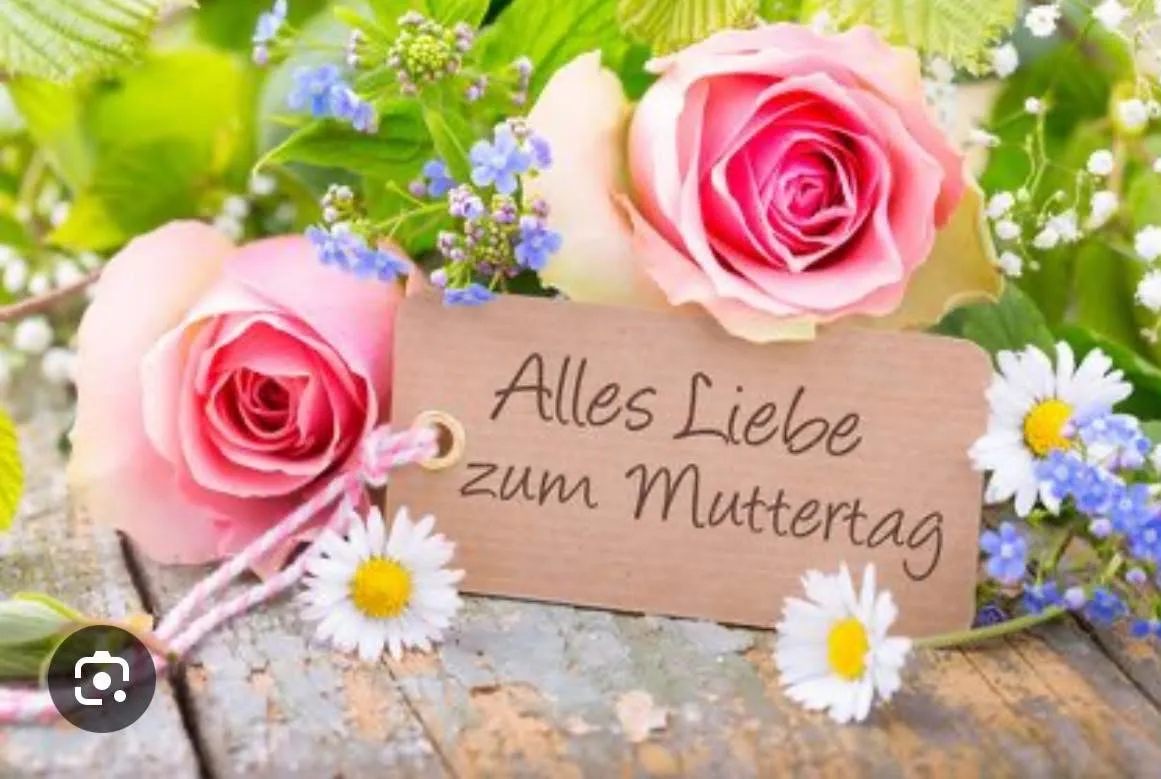 Ein Strauß aus rosa Rosen und blauen Blumen mit einem Holzschild, auf dem 'Alles Liebe zum Muttertag' steht, liegt auf einer Holzoberfläche.