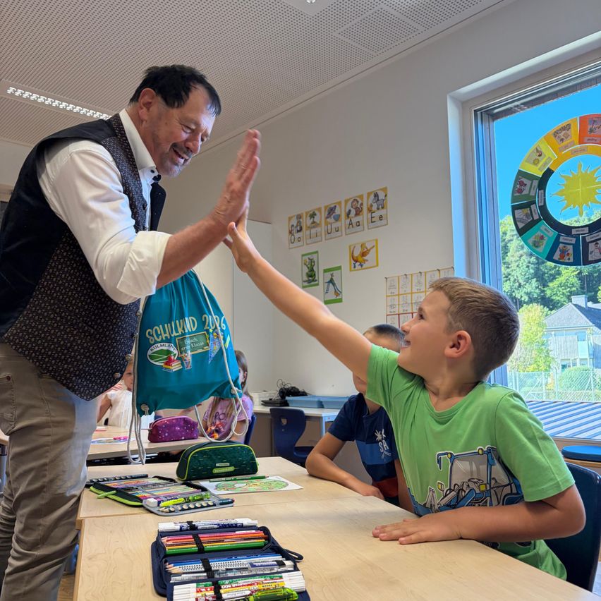 Schulkind gibt Lehrer High Five in einem Klassenzimmer in Österreich