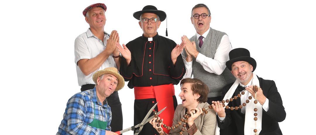 Eine Gruppe von Menschen in Kostümen posiert für ein Foto. Ein Mann hält eine Schere und eine Frau eine Rosenkranz. Ein anderer Mann hält Geld. Ein Mann in einem Priestergewand steht in der Mitte.