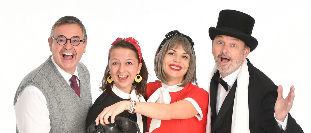 Vier Personen in Vintage-Kleidung posieren zusammen; zwei Frauen in gepunkteten Kleidern und zwei Männer, einer mit Tophut und Fliege, der andere in Weste und Krawatte.