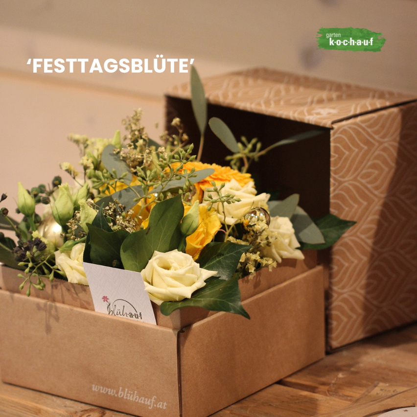 Eine braune Box enthält eine Blumenarrangement mit weißen und gelben Blumen, grünen Blättern und einer kleinen Karte. Die Box ist geöffnet und zeigt die Blumen. Eine weitere ähnliche Box befindet sich dahinter. Das Bild hat einen Wasserzeichen mit dem Text 'garten k-o-c-h-a-u-f'.