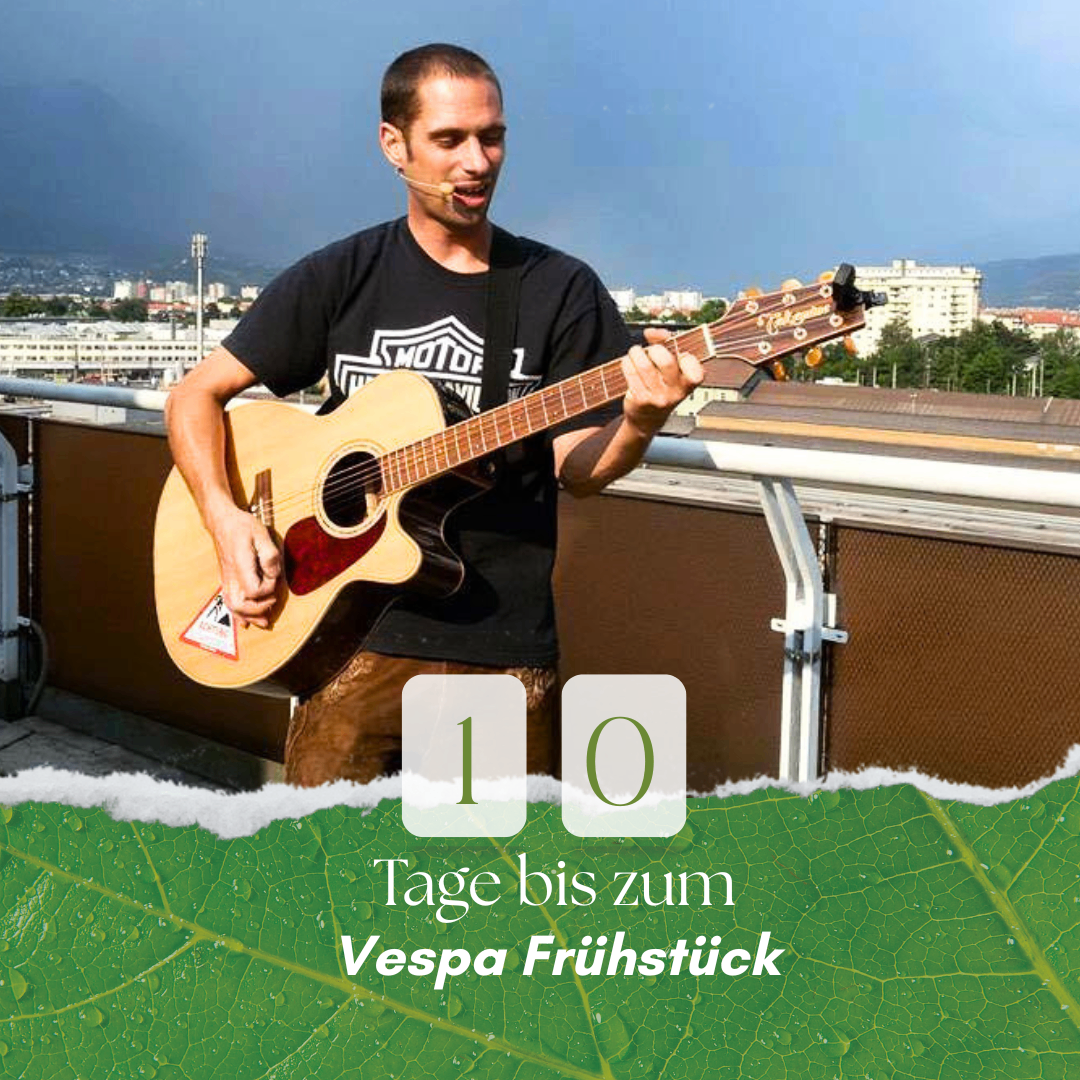 A man stands on a balcony, holding a guitar, and singing with a microphone. He wears a black shirt with the Harley-Davidson logo. Below him is text stating '10 days until the Vespa breakfast'.