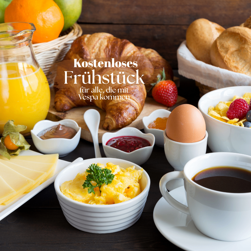 A breakfast spread includes croissants, eggs, cereal, fruit, cheese, and coffee. There is also a pitcher of orange juice and a bowl of jam.