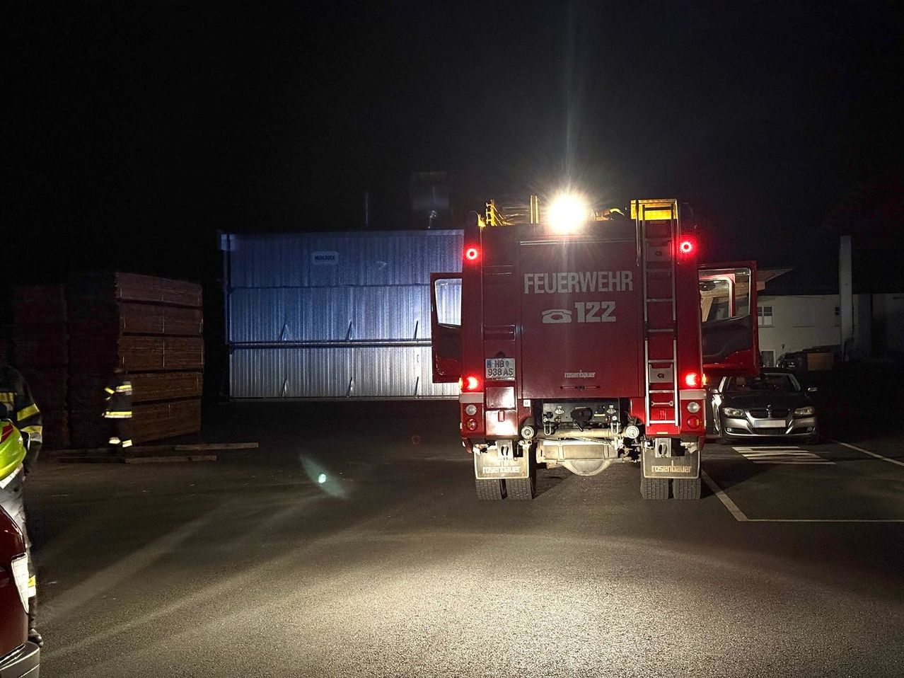 Ein Feuerwehrwagen mit eingeschalteten Lichtern steht nachts auf einem Parkplatz.