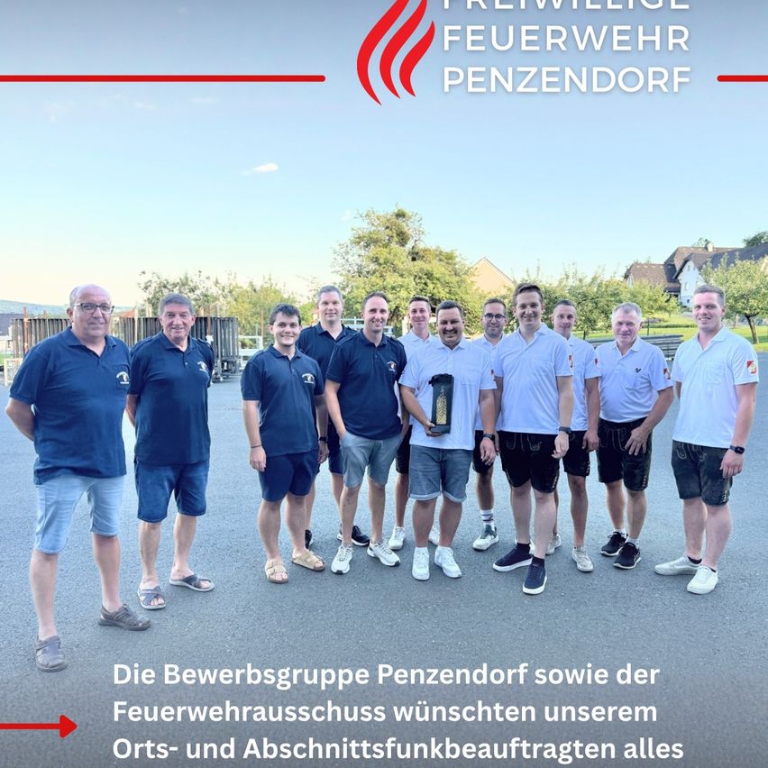 Eine Gruppe von Männern, alle in passenden Uniformen gekleidet, steht gemeinsam auf einem Parkplatz. Sie halten eine Trophäe in der Mitte. Die Worte 'Freiwillige Feuerwehr Penzendorf' sind über ihnen.