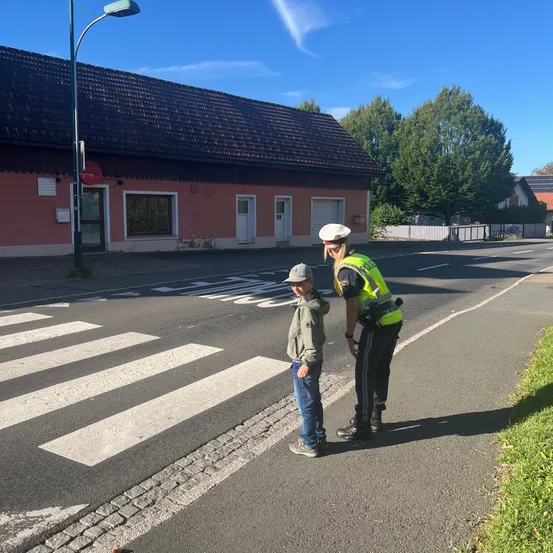 Ein Polizist spricht mit einem jungen Jungen an einem Zebrastreifen.