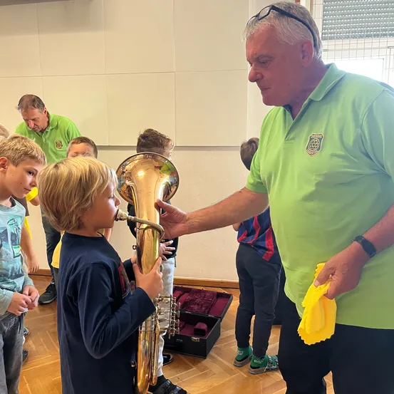 Ein Mann zeigt einem kleinen Jungen, wie man eine Tuba in einem Klassenzimmer spielt.