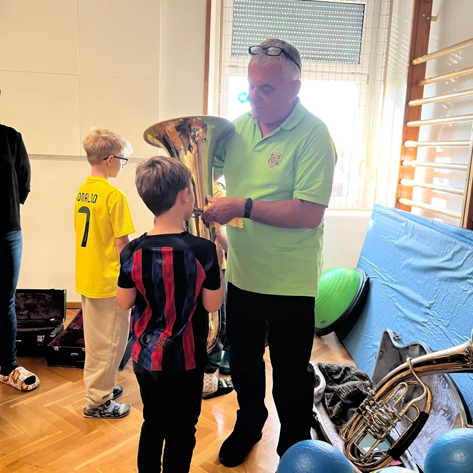 Ein erwachsener Mann hält eine Tuba, während ein junger Junge zusieht.