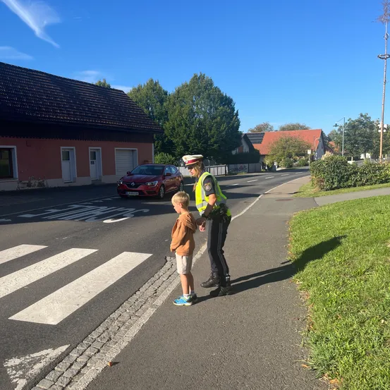 Ein Polizist spricht mit einem kleinen Jungen auf dem Bürgersteig einer Straße.