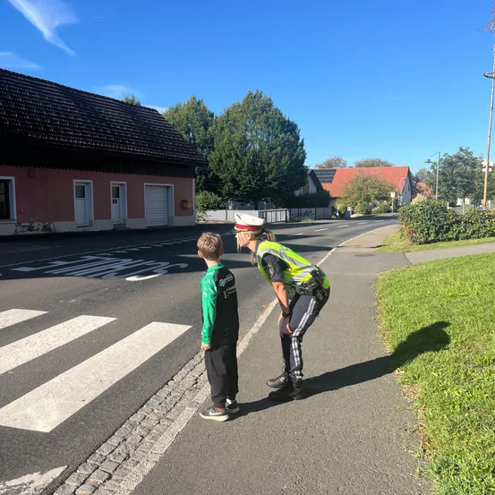 Ein Polizist bringt einem kleinen Jungen bei, wie man die Straße überquert.