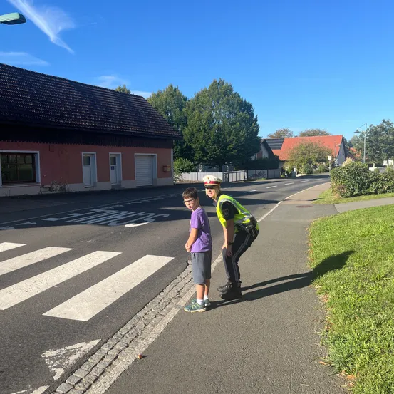 Ein Verkehrspolizist spricht mit einem jungen Jungen vor einem Zebrastreifen an einem sonnigen Tag.