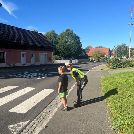 Ein Verkehrspolizist hilft einem kleinen Jungen, die Straße an einem Zebrastreifen zu überqueren.