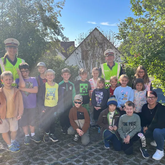 Eine Gruppe von Kindern und zwei Erwachsenen posiert für ein Foto vor einem Haus.