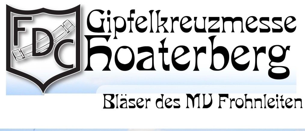 Eine Gruppe von Menschen, möglicherweise Pilger, geht in einem Grasbereich. Ein Kreuz ist auf der linken Seite. Viele Menschen sitzen auf dem Gras und einige stehen. Eine große Gruppe von Menschen ist auf dem Berg.