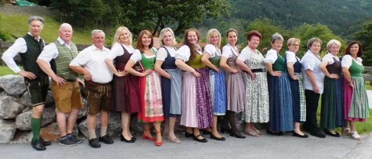 Eine Gruppe von Menschen in traditioneller Kleidung posiert für ein Foto mit Bergen im Hintergrund.