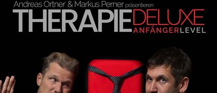 Two men standing next to a red object with a tie. The left man wears a Ghostbusters t-shirt. Event details for 19.09.2026 at Volkshaus Frohnleiten, Josef Ortisstraße 9, 8130 Frohnleiten.