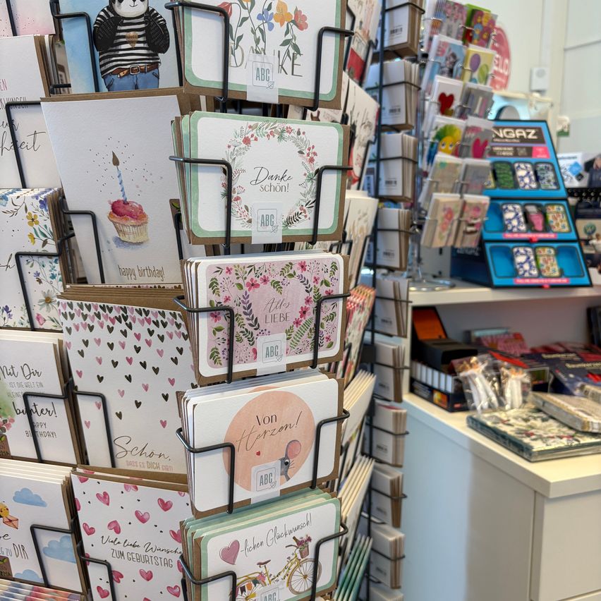 A display of greeting cards in a shop, featuring cards for birthdays, love, and other occasions. Each card has unique designs and text.