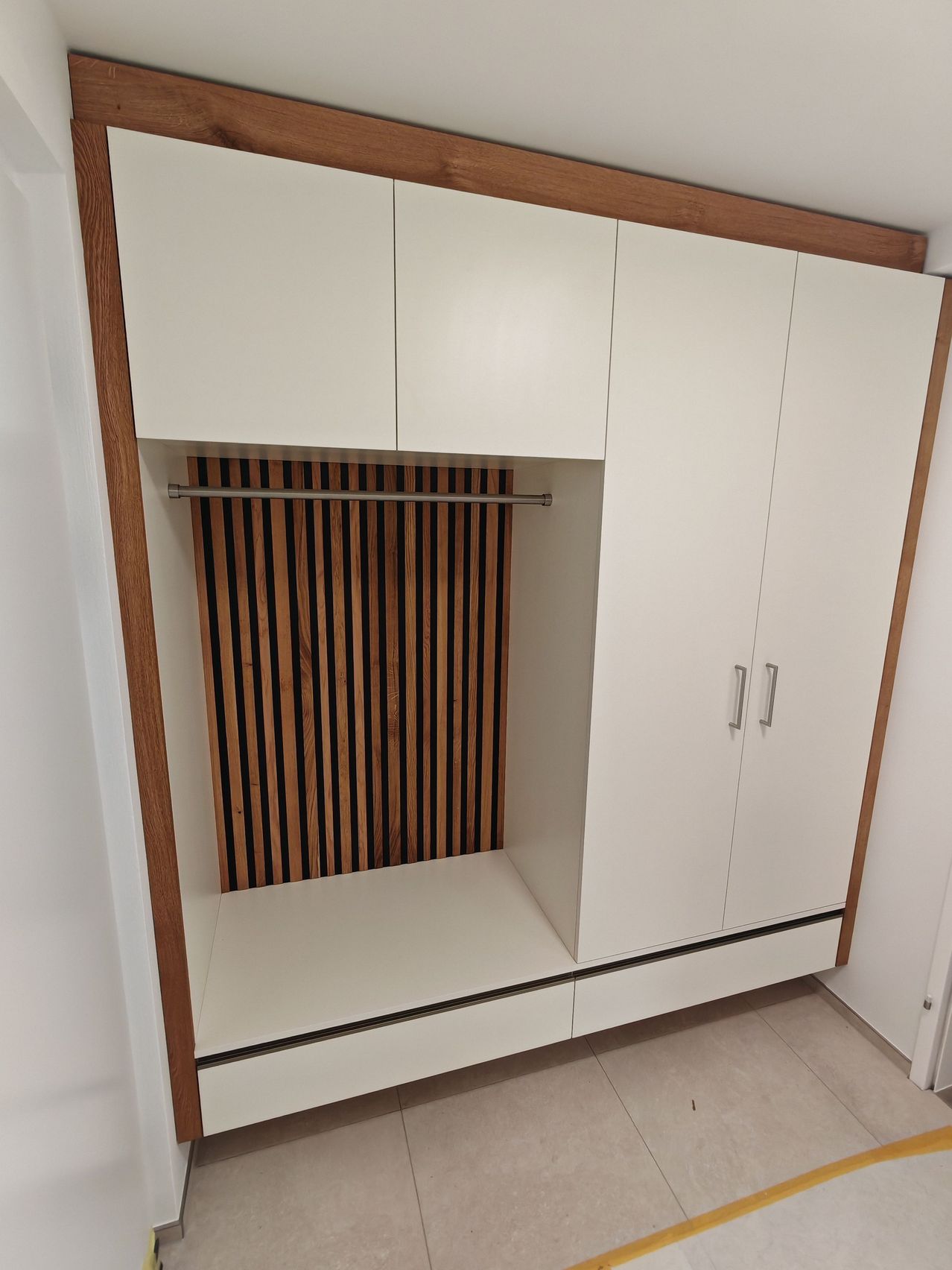 A white wooden wardrobe with a wooden frame, featuring two large doors and two smaller doors above a bench and a hanging rail.