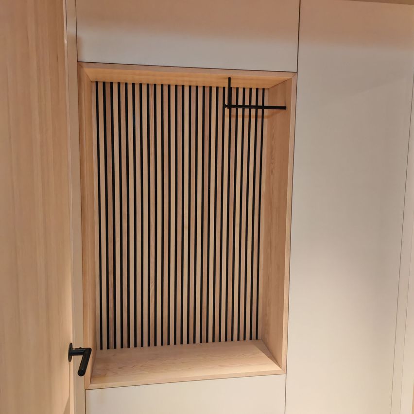Eine Nahaufnahme einer Holztür mit Gitterdesign. Die Platte ist Teil eines Kleiderschranks und hat einen Holzrahmen und schwarze vertikale Streifen.