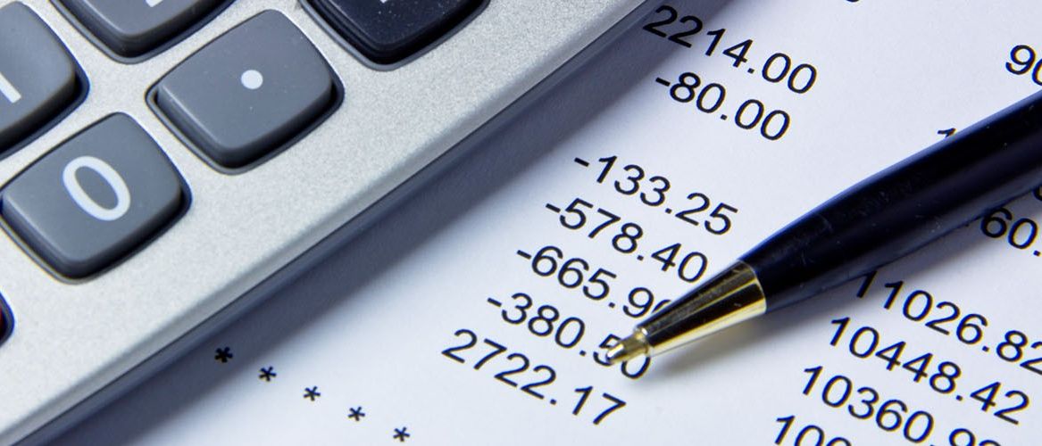 Ein Taschenrechner liegt auf einem Finanzbericht mit Zahlen wie -80,00, -133,25, -578,40, -665,90, -380,50 und 2722,17. Ein Stift liegt ebenfalls auf dem Bericht.