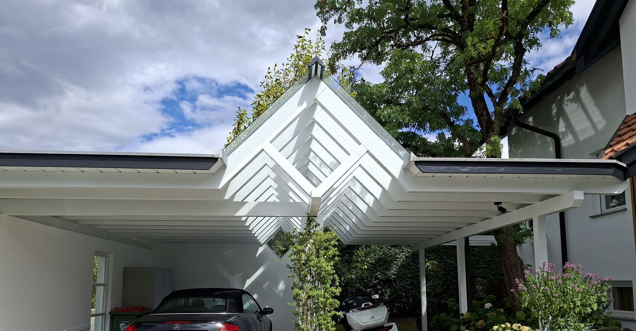 Ein modernes Carport mit weißem Dach und geometrischen Mustern, das einen schwarzen Mercedes und ein weißes Motorrad unter einem klaren blauen Himmel beherbergt.
