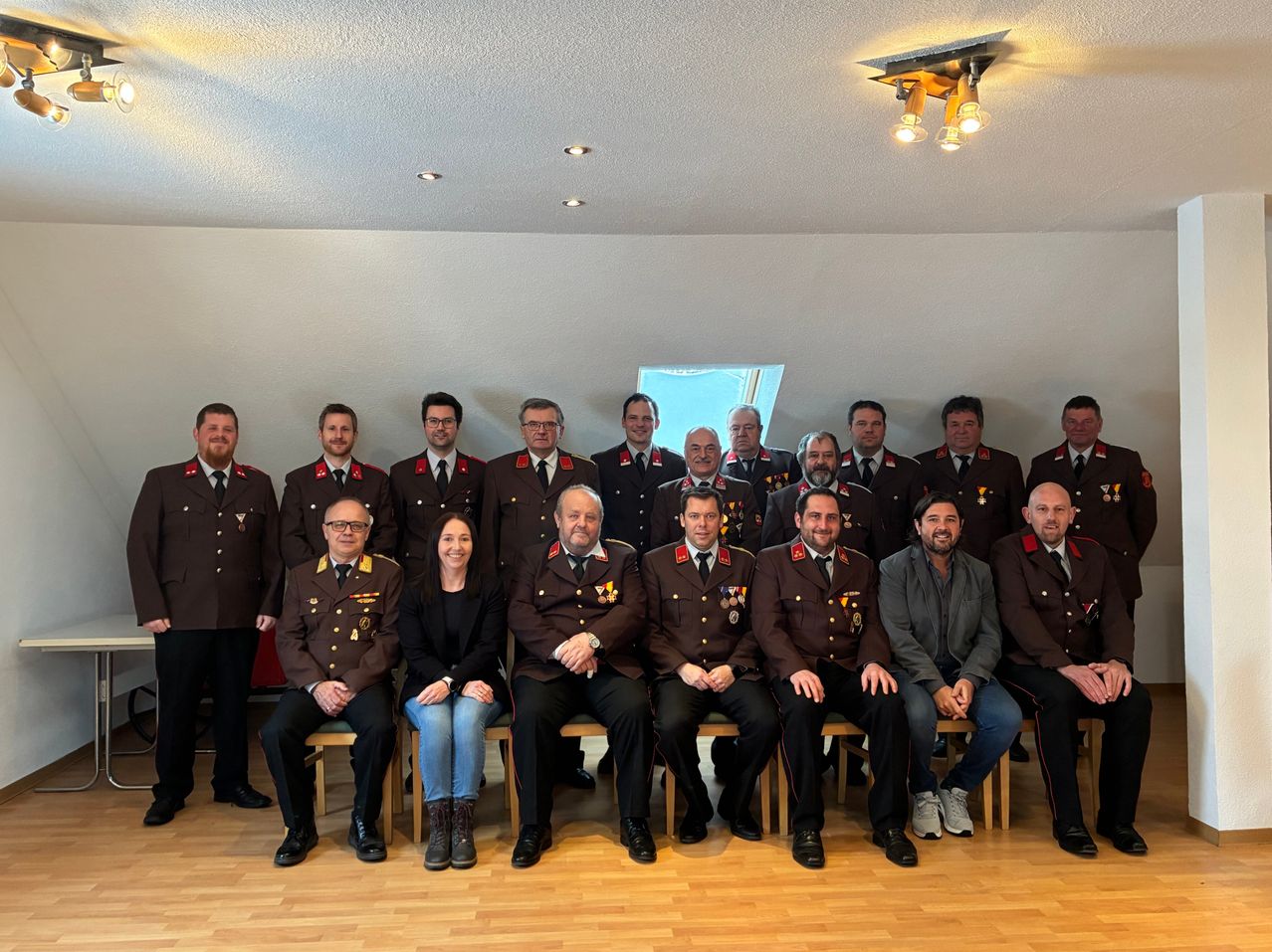 Eine Gruppe uniformierter Personen, einschließlich Männer und eine Frau, posiert für ein Foto in einem Raum.