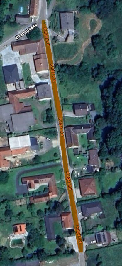 Eine Luftaufnahme eines Dorfes mit mehreren Gebäuden, Straßen und Bäumen. Die Hauptstraße ist in Gelb hervorgehoben.