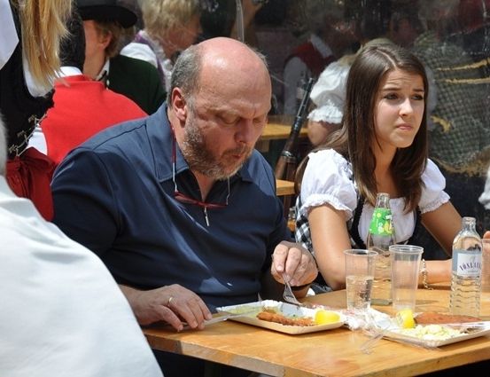 Ein Mann und eine Frau sitzen an einem Tisch und essen. Der Mann hält eine Gabel und ein Messer.