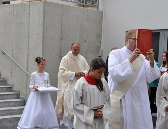 Eine Gruppe von Priestern und jungen Mädchen in weißen Gewändern gehen eine Betontreppe hinunter.