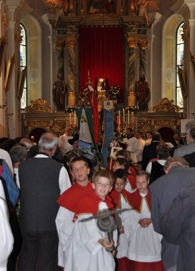 Eine Gruppe von Kindern in roten und weißen Gewändern steht vor einem Kirchenaltar.