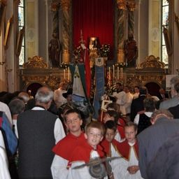 Eine Gruppe von Kindern in roten und weißen Gewändern steht vor einem Kirchenaltar.