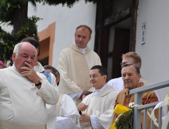 Eine Gruppe von Priestern steht vor einer Kirche, einer von ihnen bedeckt seinen Mund mit der Hand.