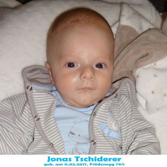 Ein Babyjunge namens Jonas Tschiderer, geboren am 11.02.2017, liegt auf einer weißen Decke und trägt ein blaues Shirt mit einem Bären und den Worten 'Be Brave' darauf.
