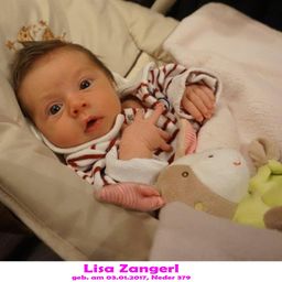 Ein Babymädchen namens Lisa Zangerl, geboren am 3. Januar 2017, liegt in einem Kinderbett mit Spielzeug, in einem rot-weiß gestreiften Outfit.