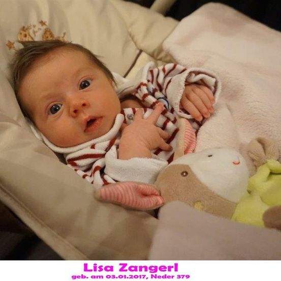 Ein Babymädchen namens Lisa Zangerl, geboren am 3. Januar 2017, liegt in einem Kinderbett mit Spielzeug, in einem rot-weiß gestreiften Outfit.
