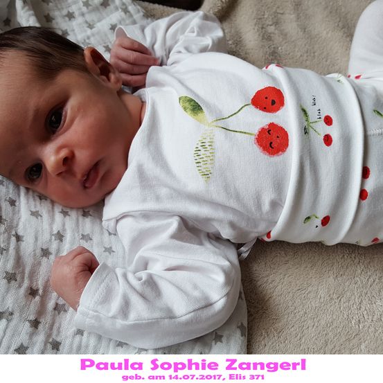 Ein Babymädchen namens Paula Sophie Zangerl, geboren am 14.07.2017, liegt auf einem Bett und trägt ein weißes Onesie mit Kirschdesign.