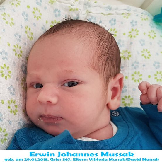 Ein Neugeborenes namens Erwin Johannes Mussak, geboren am 29. Januar 2018, liegt auf einer blumengemusterten Decke und trägt ein blaues Shirt. Seine Augen sind leicht geöffnet, und er hat etwas Speichel an den Lippen.