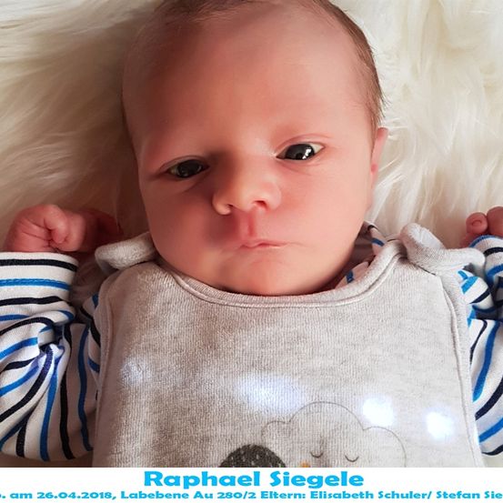 Ein Babyjunge namens Raphael Siegel liegt auf einer weißen Pelzdecke, trägt ein gestreiftes Shirt und eine graue Schürze mit Wolkendesign. Das Bild ist vom 26. April 2018.