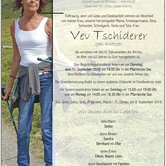 Eine Frau in einem weißen Tanktop und Jeans steht auf einem Pfad mit einem Wanderstock und blickt nach vorne. Im Hintergrund ist eine Gedenkanzeige sichtbar, die die Beerdigungsarrangements für eine Person namens Vev T. Schiderer beschreibt.