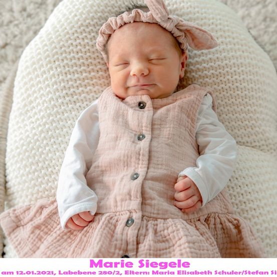 Ein Babymädchen in einem rosa Kleid und weißen langen Ärmeln schläft friedlich auf einer weißen gestrickten Decke. Das Baby trägt eine rosa Kopfband mit Schleifenohr. Das Bild enthält den Namen des Babys, Geburtsdatum und Namen der Eltern.